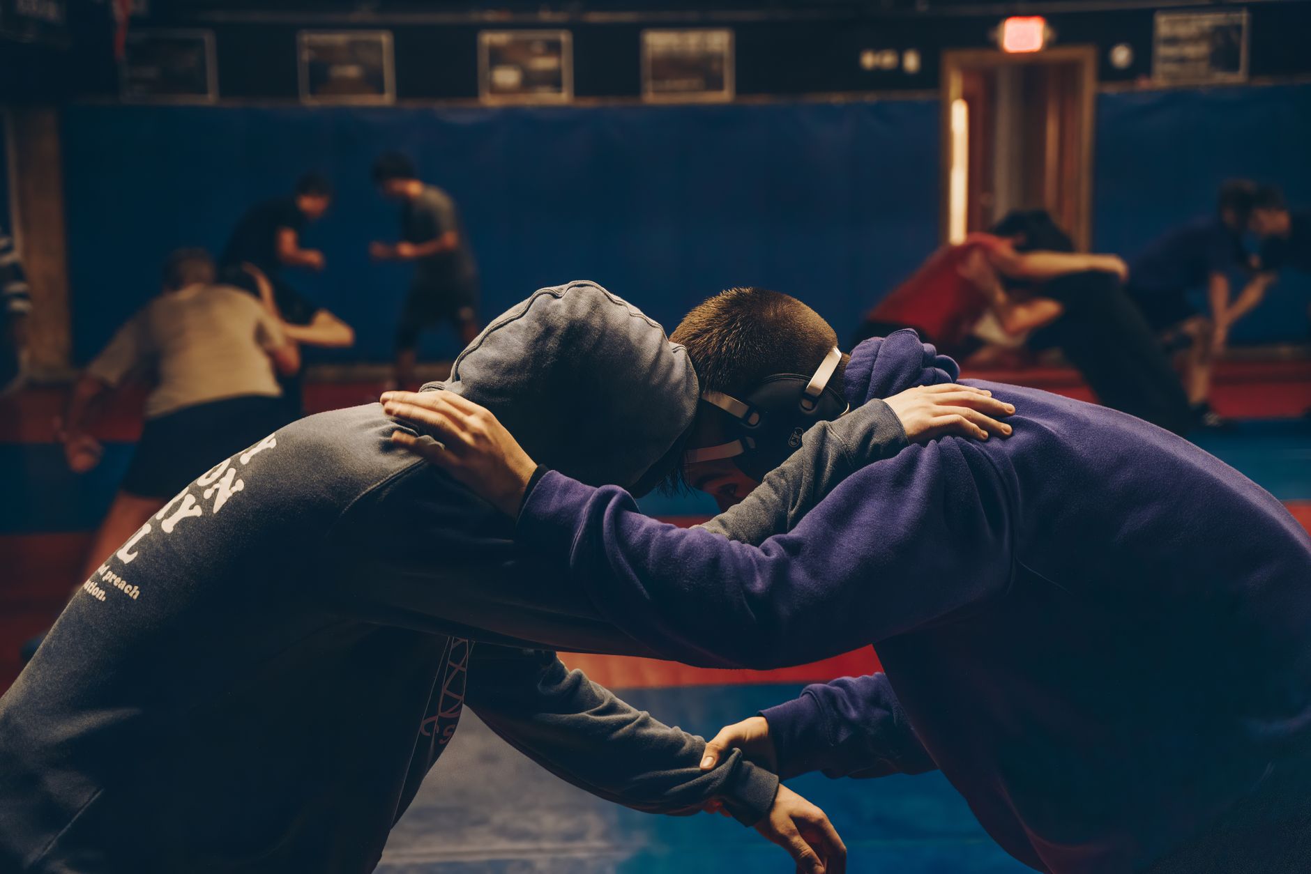 Deux sportifs en corps-à-corps à l'entraînement, mains sur la nuque de l'autre