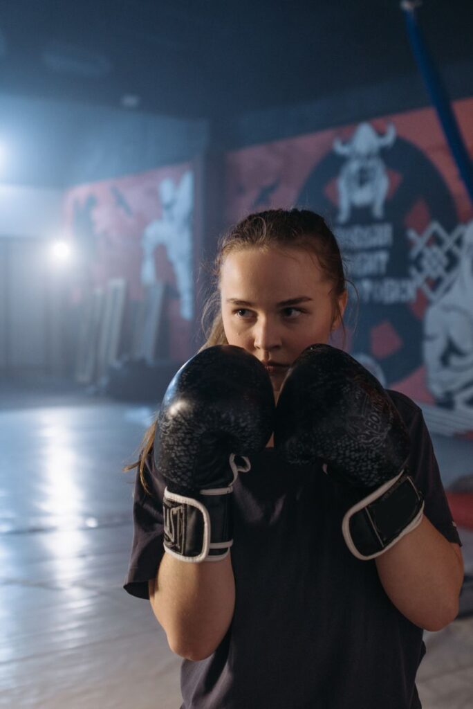 Boxeuse en garde haute, les deux gants devant le visage