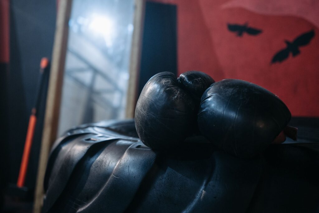 Gants de boxe noirs posés sur un pneu dans une salle peu éclairée