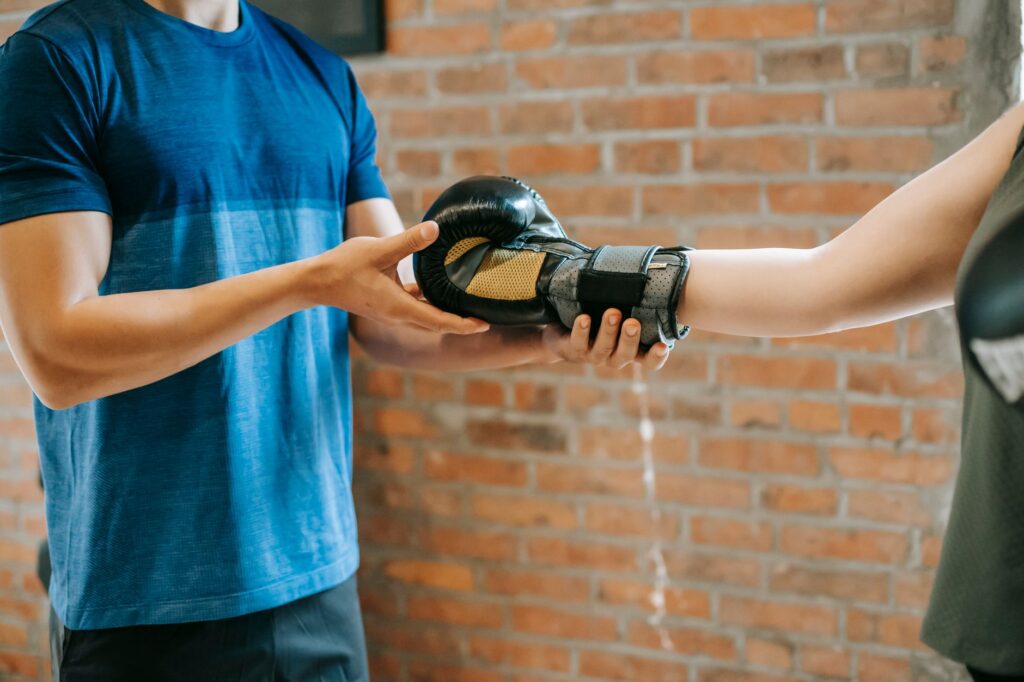 Entraîneur qui aide une élève à enfiler son gant de boxe