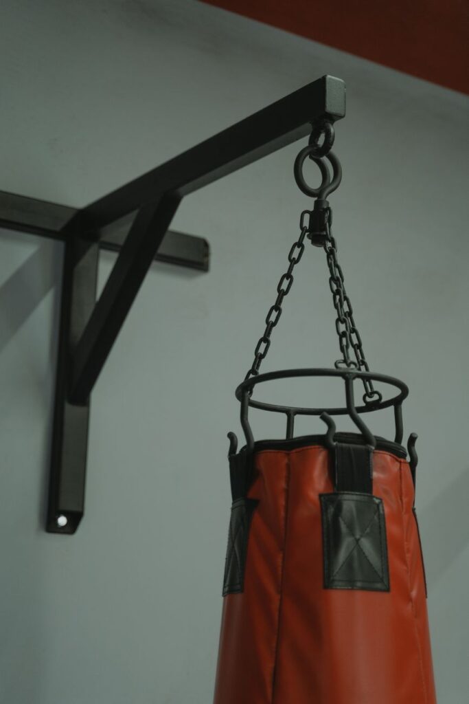 Sac de frappe suspendu à une potence murale par ses chaînes
