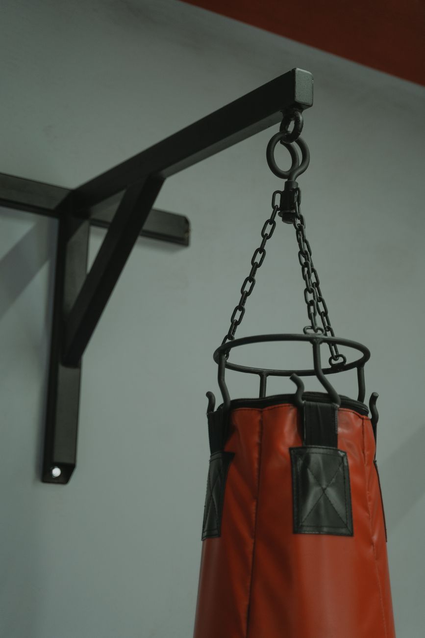 Sac de frappe suspendu à une potence murale par ses chaînes
