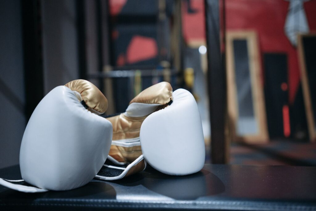 Paire de gants de boxe blancs et dorés posée dans une salle