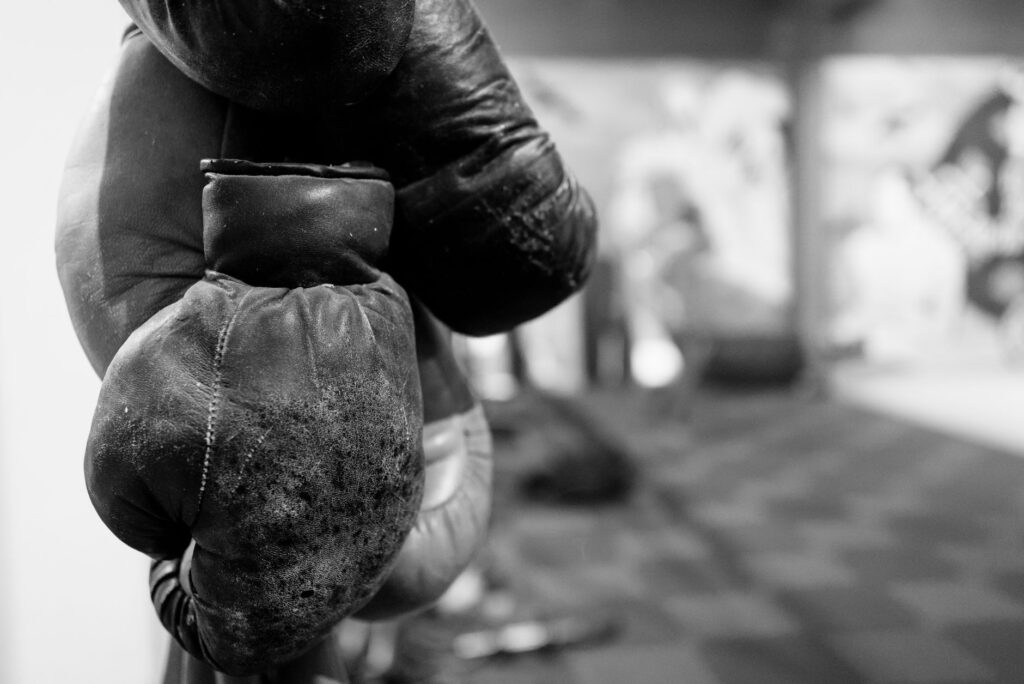 Gants de boxe en cuir usé suspendus, photo en noir et blanc