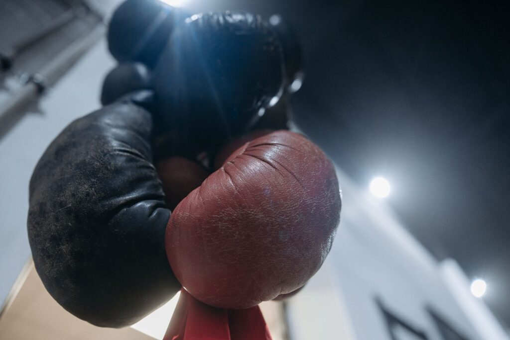 Gants de boxe usés, un noir et un rouge, suspendus dans une salle