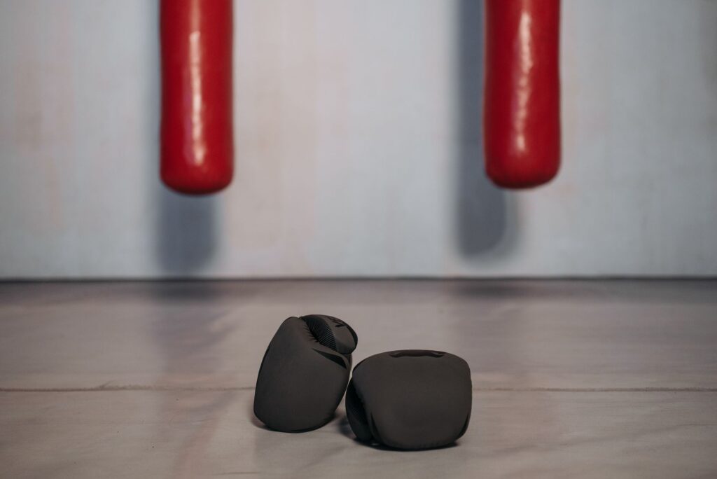 Gants de boxe noirs posés au sol sous deux sacs de frappe