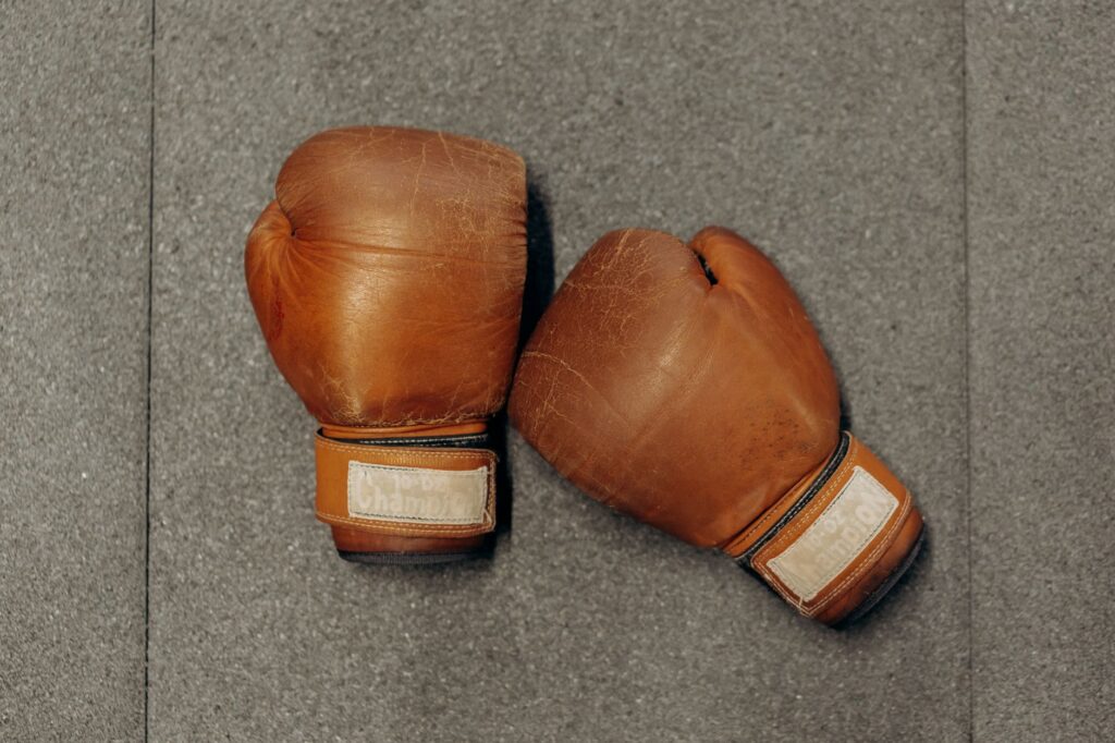 Paire de gants de boxe en cuir marron posée au sol