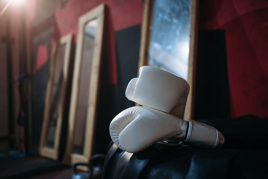 Paire de gants de boxe blancs posée dans une salle aux murs rouges